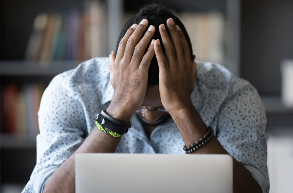 Person feeling overwhelmed while working at a laptop